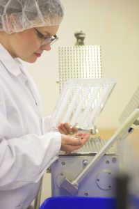 Ellen produserer reinleverkapslene for hånd med en manuell kapselmaskin.